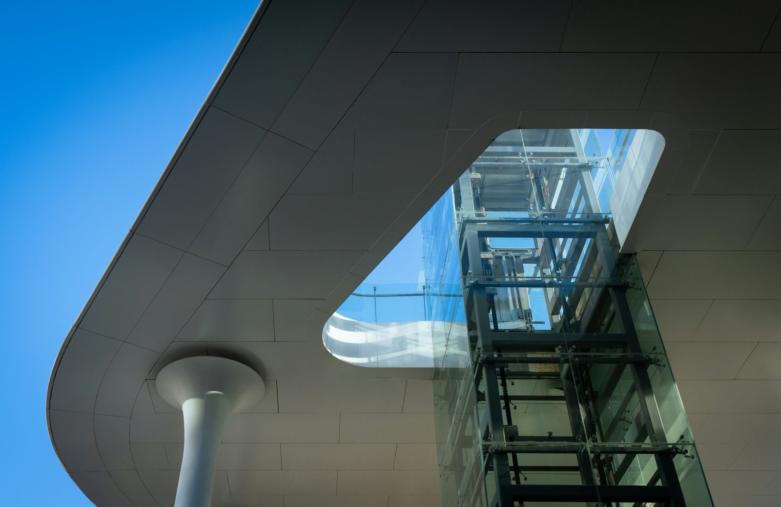 Modern building with glass elevator and blue sky